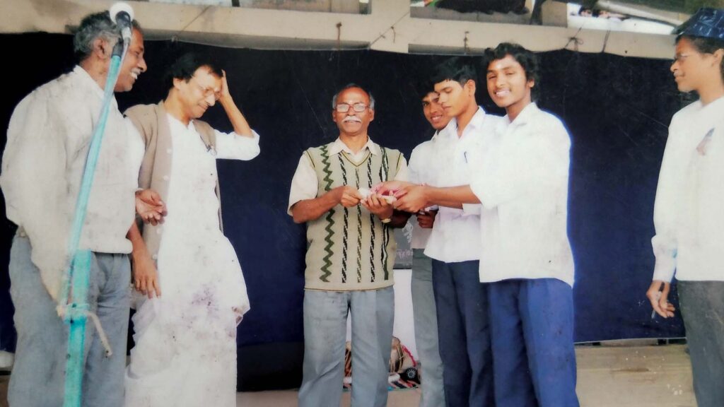 Asgar Molla receiving an award with friends from Sukumar Paira Sir and other teachers on school stage