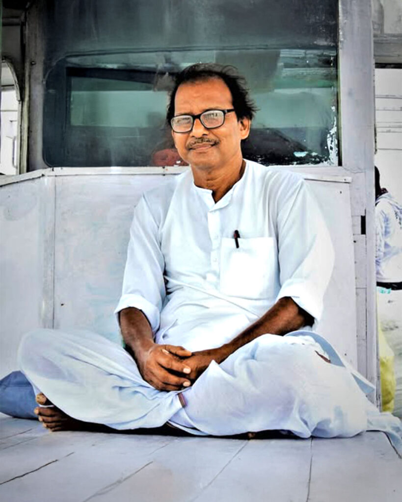 Sukumar Paira, principal of Bijoynagar Adarsha Vidyamandir (H.S), sitting peacefully in traditional attire.