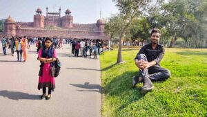 A split-image showing a woman standing in front of the Red Fort entrance with a crowd, and a man sitting peacefully on green grass under trees.