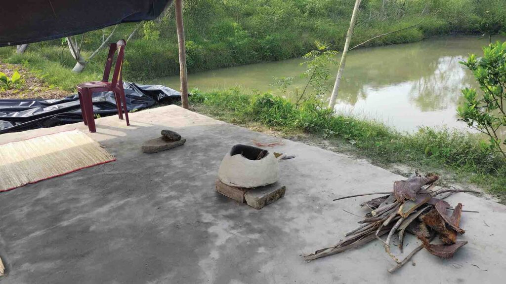 Traditional outdoor mud stove setup beside a pond in rural Sundarban, West Bengal.