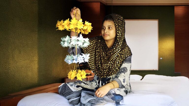 Artist Tahamina Molla holding her handmade paper flower hanging craft