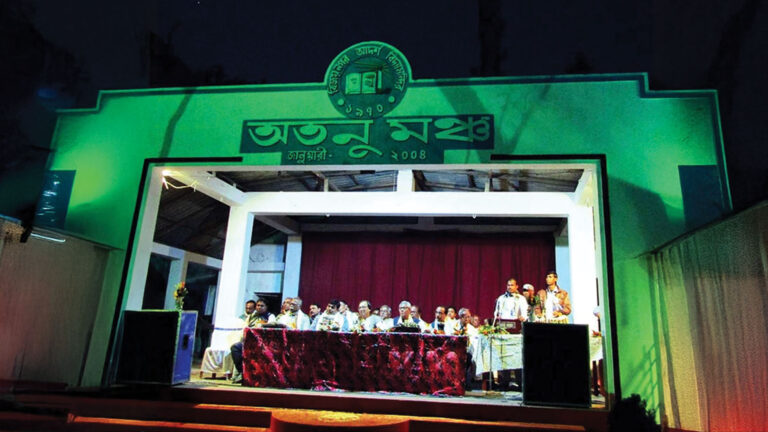 Stage program at Bijoynagar Adarsha Vidyamandir Golden Jubilee celebration with teachers, alumni, and guests under green lighting.