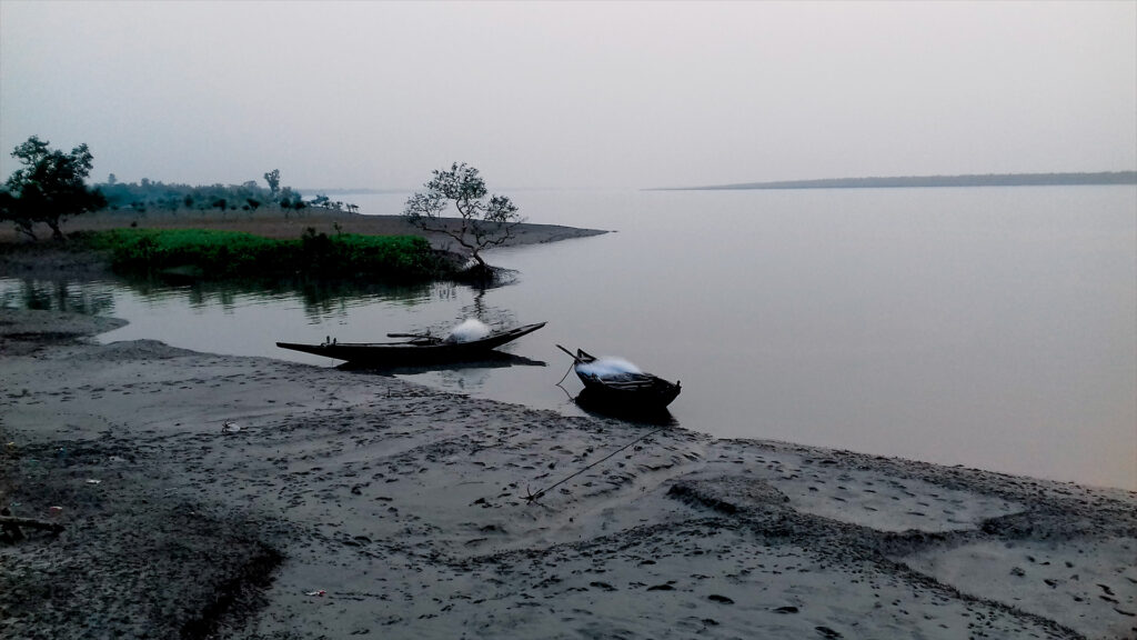 Two small fishing boats anchored on the muddy riverbank at Bally Ferry Ghat in Sundarban during early morning.